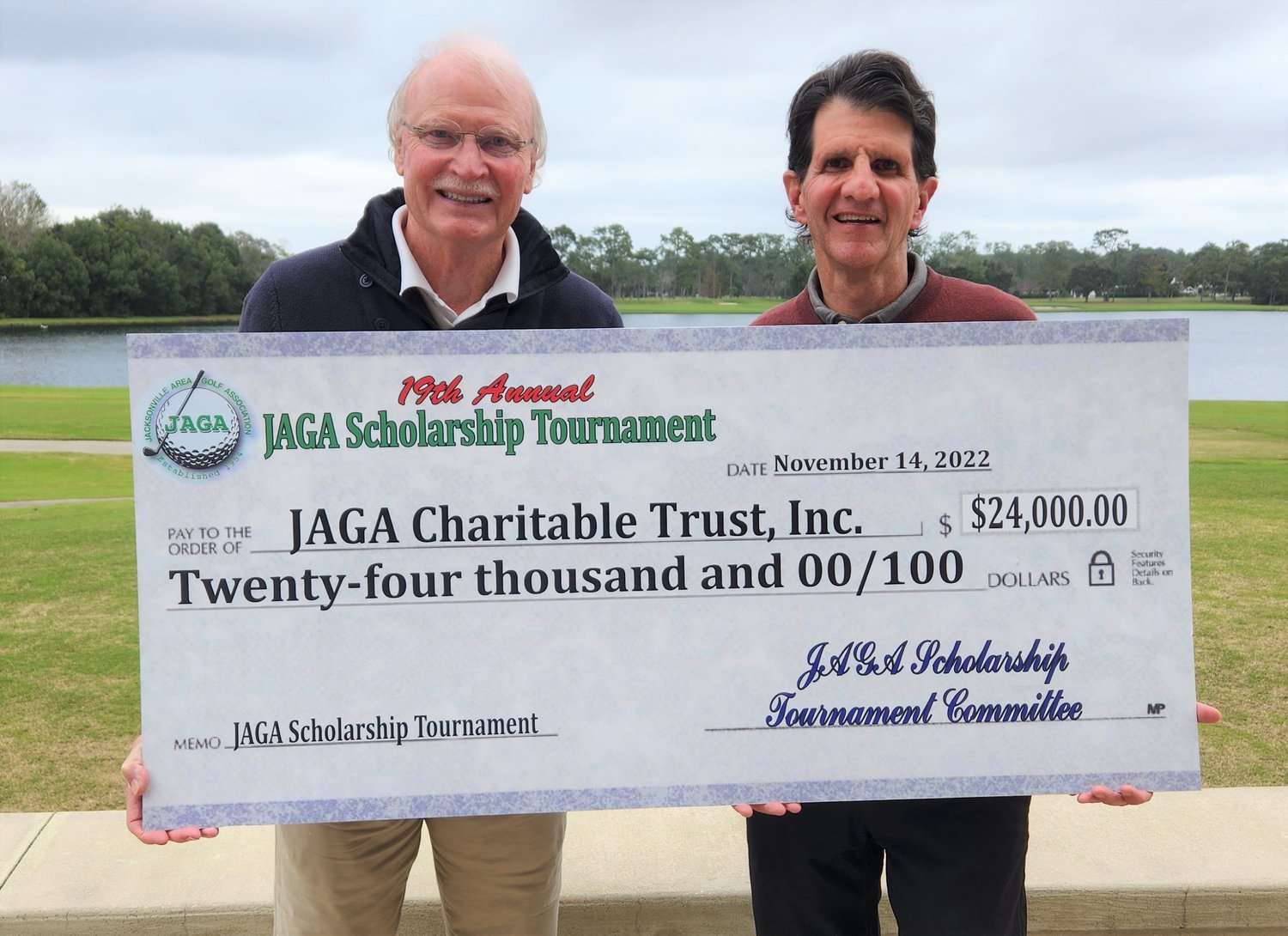 JAGA Scholarship Golf Classic chairman Michael McKenny, left, and JAGA president Jeff Adams 
unveil a check in the amount of $24,000 to benefit the JAGA scholarship program.